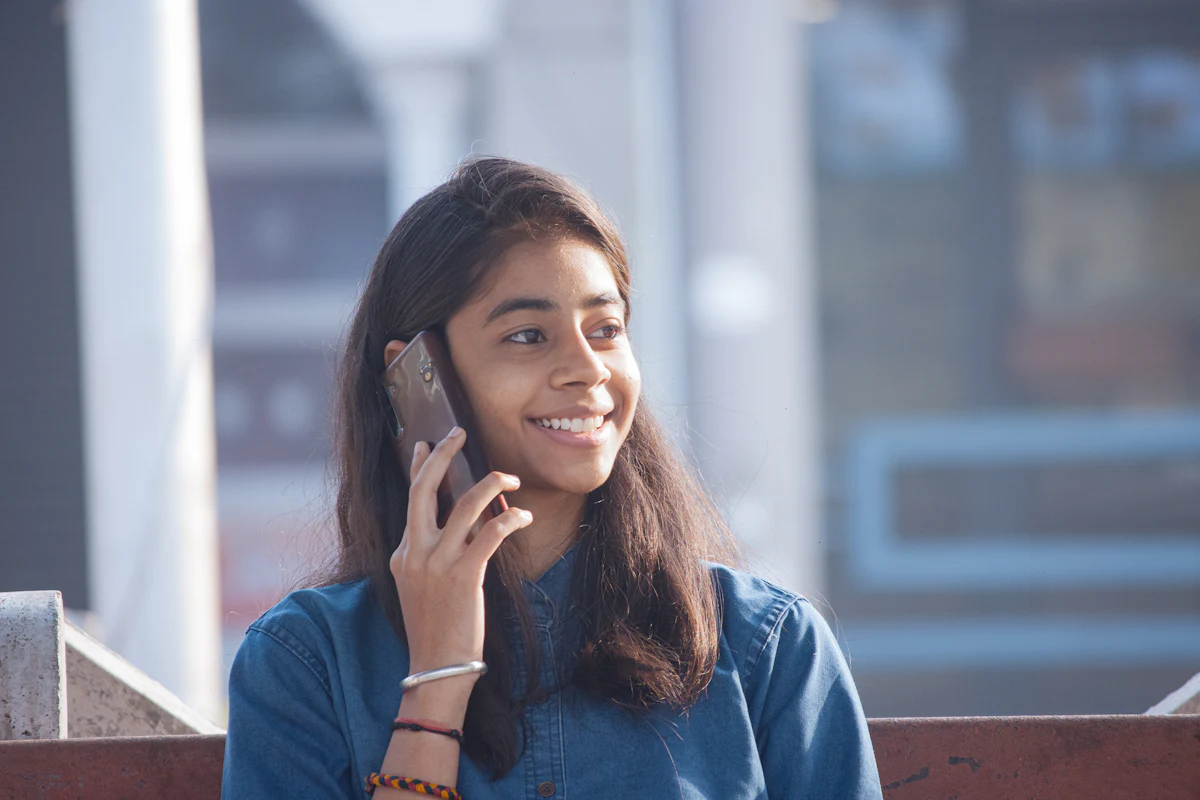 A young woman smiling as she talks on her phone
